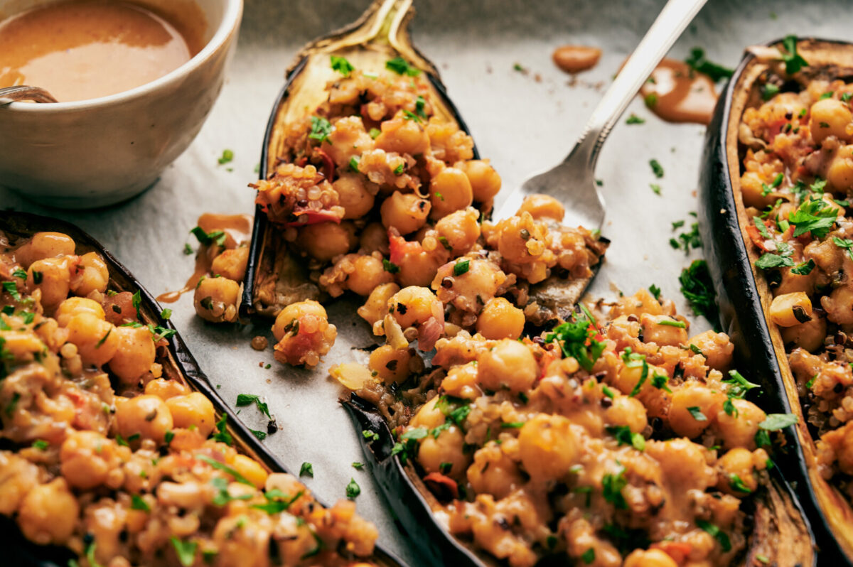 Closeup view of chickpea and quinoa stuffed eggplants on a parchment lined baking sheet.