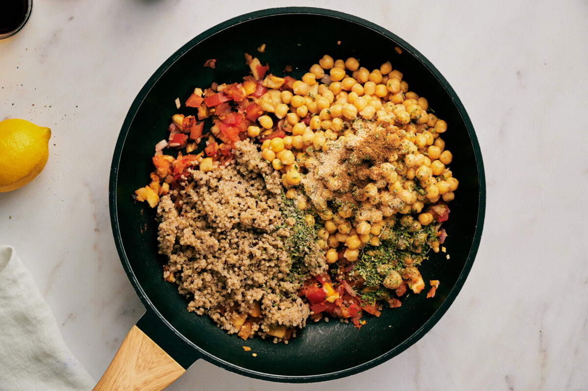 Stuffing ingredients for quinoa stuffed eggplants in a black skillet.