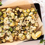 Roasted Cauliflower & Brussels Sprouts with Parmesan cheese on a parchment lined baking sheet.