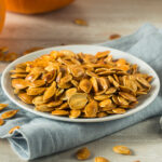 Roasted pumpkin seeds on a while plate.