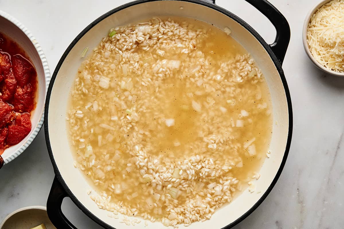 Wine and stock added to the rice and onion mixture in a large pan.