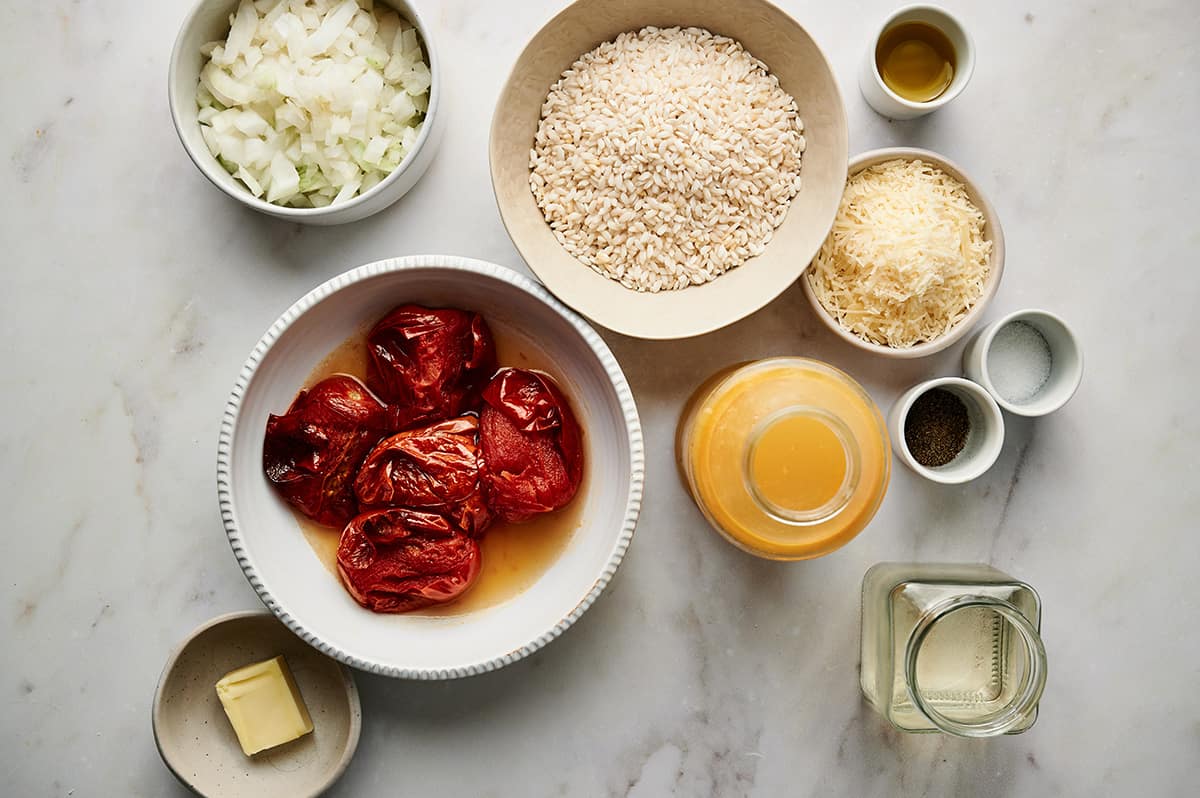 Roasted tomato risotto ingredients: Rice, onion, roasted tomatoes, onion, parmesan cheese, white wine, butter, oil, and salt and pepper.