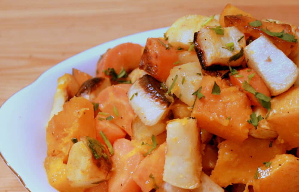 Roasted root vegetables seasoned with cardamom on a white plate.