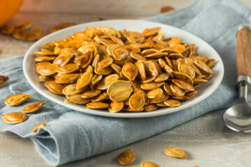 Roasted pumpkin seeds on a while plate.