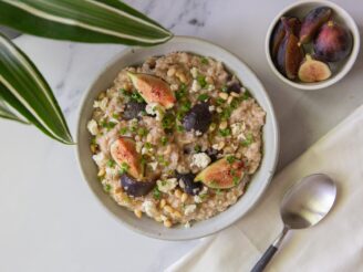 A white bowl filled with savory oatmeal with figs and feta and a napkin with a spoon with a small bowl filled with figs.