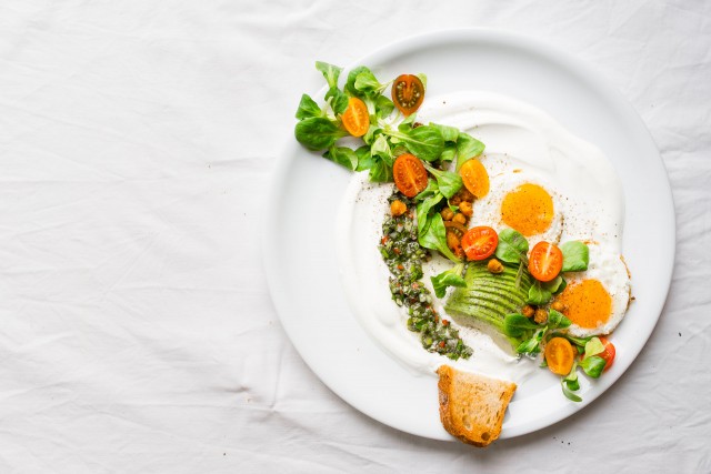 top down image of savory yogurt chimichurri salad in a plate topped with spicy roasted chickpeas, slice avocado, tomatoes and eggs on the side
