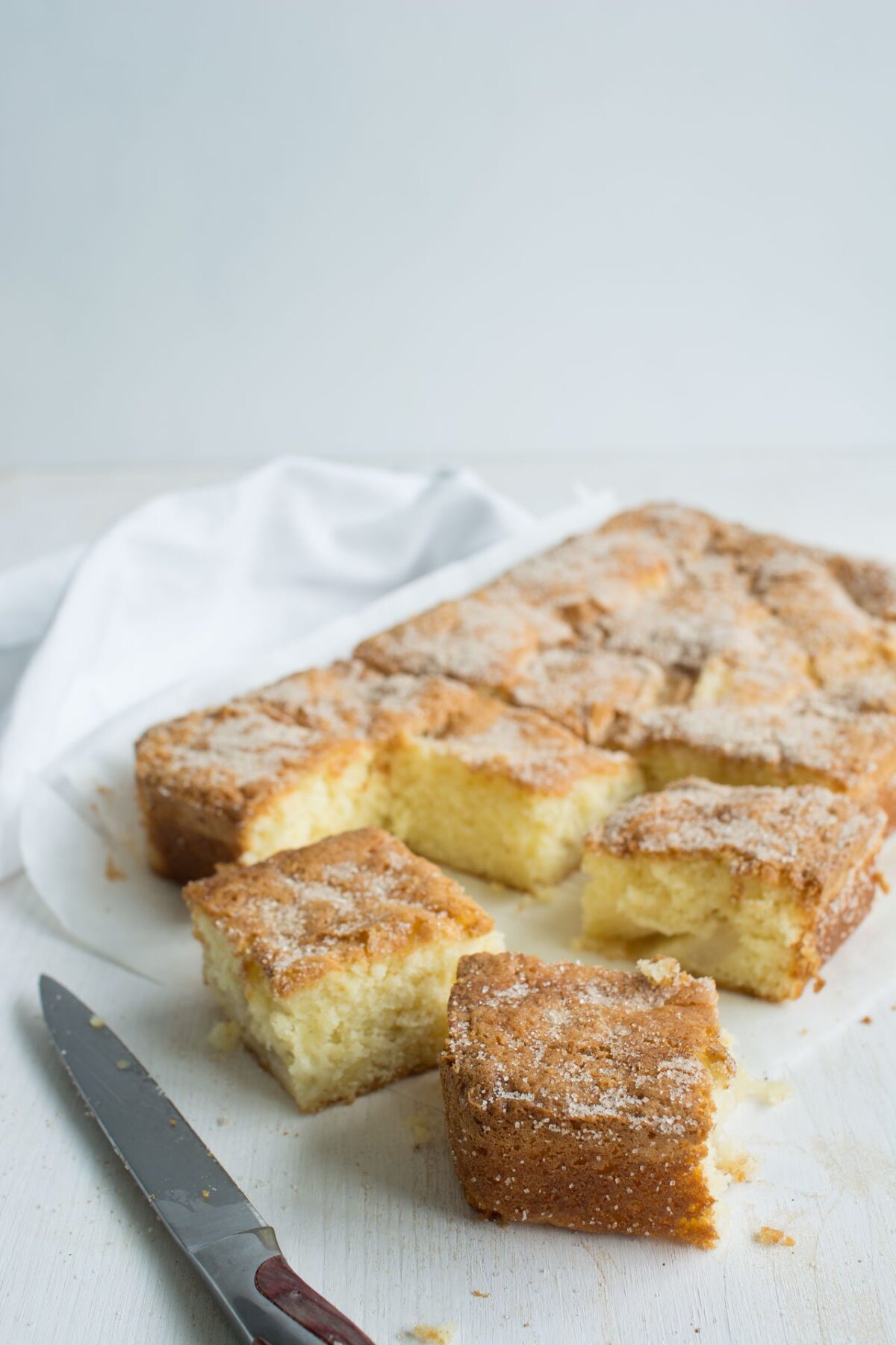 Side view image of a single layer of cinnamon spiced pear cake cut into slices.