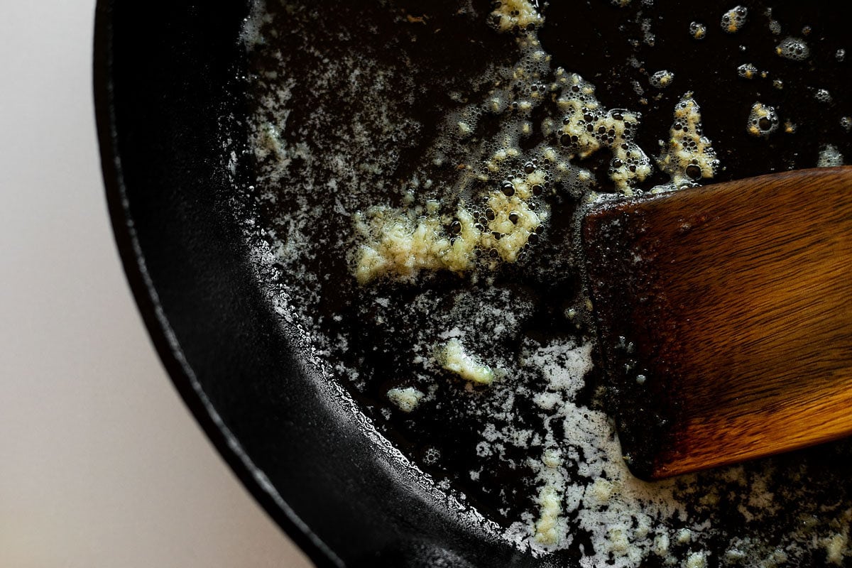 Sautéing garlic in butter in a cast iron skillet.