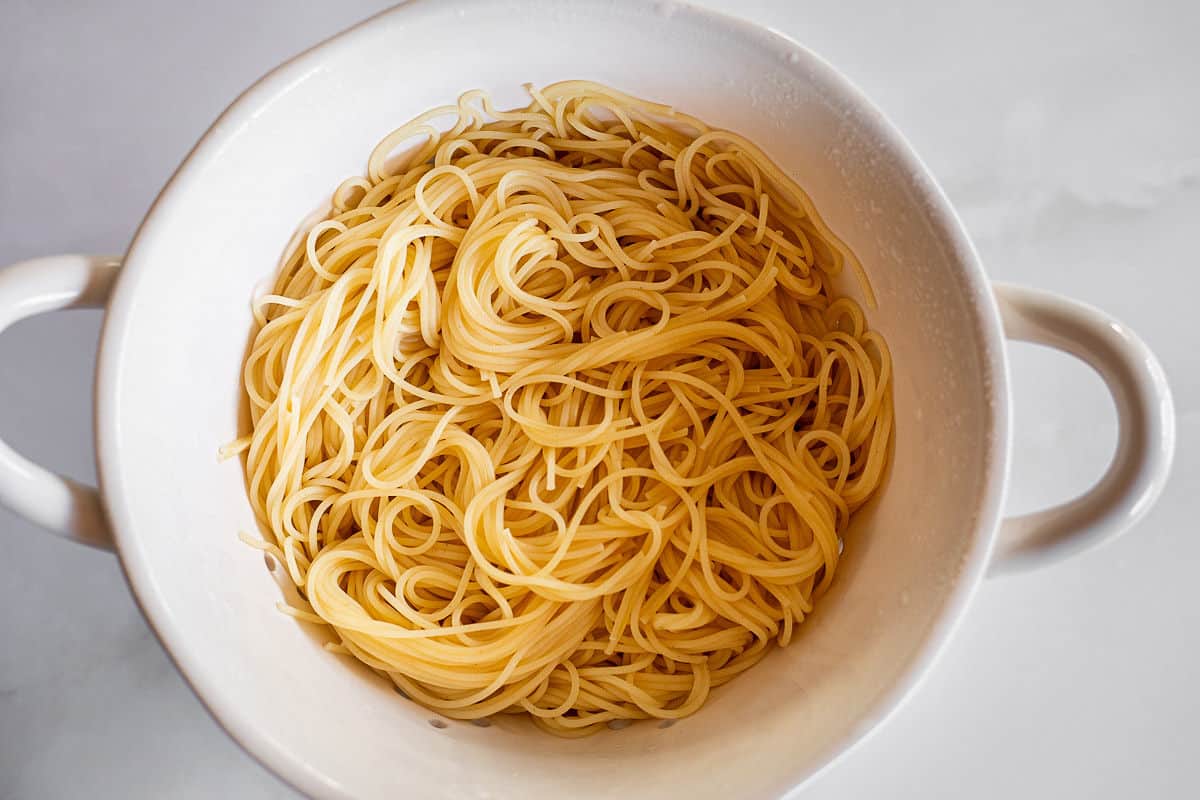 Angel hair pasta being drained in a colander.