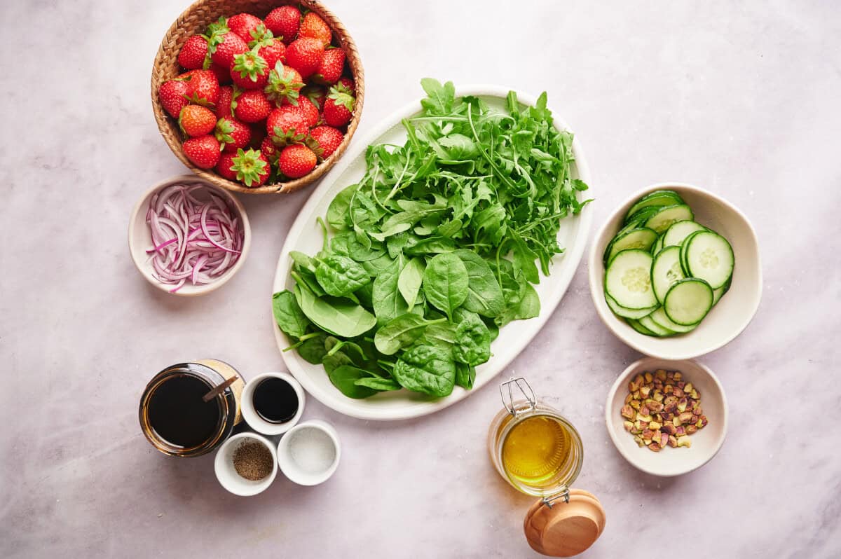 Ingredients for a Strawberry Summer Salad on a marble countertop.