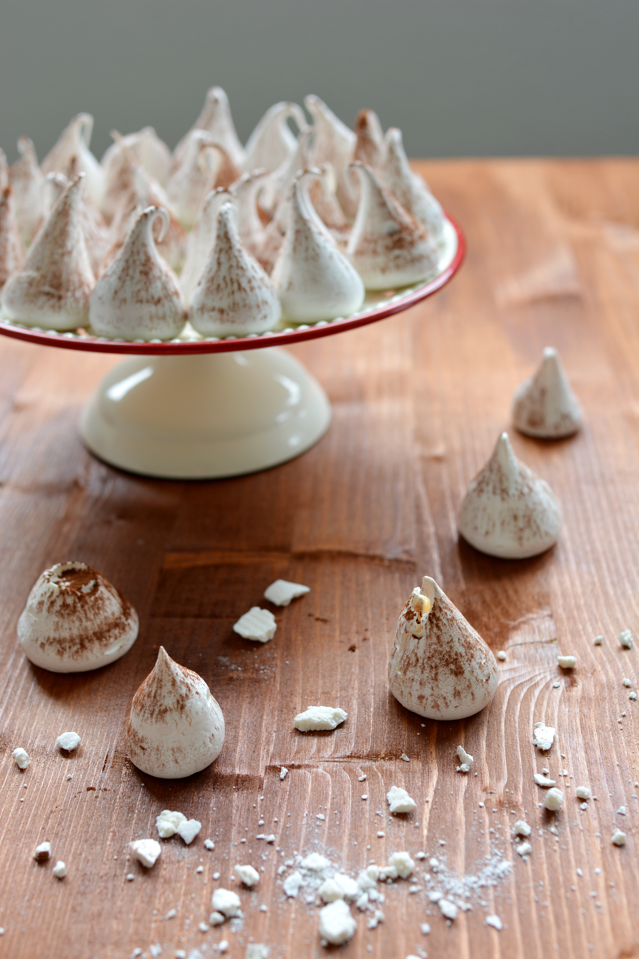 a group of swiss meringue kisses placed on the cake table, with a few scattered below