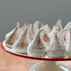 ac ropped image of a batch of swiss meringue kisses arranged on top of the cake table