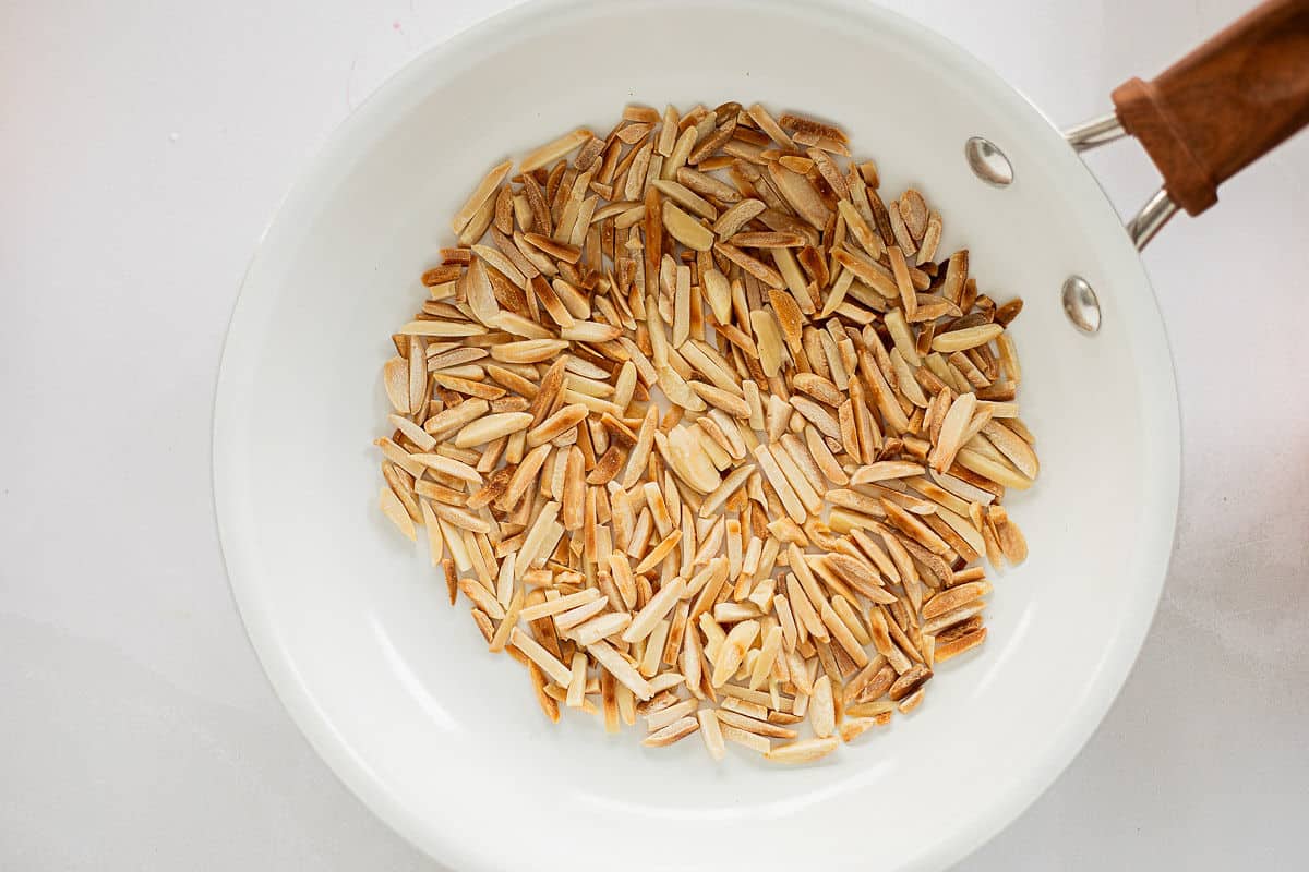 Toasting almonds in a white enamel skillet.