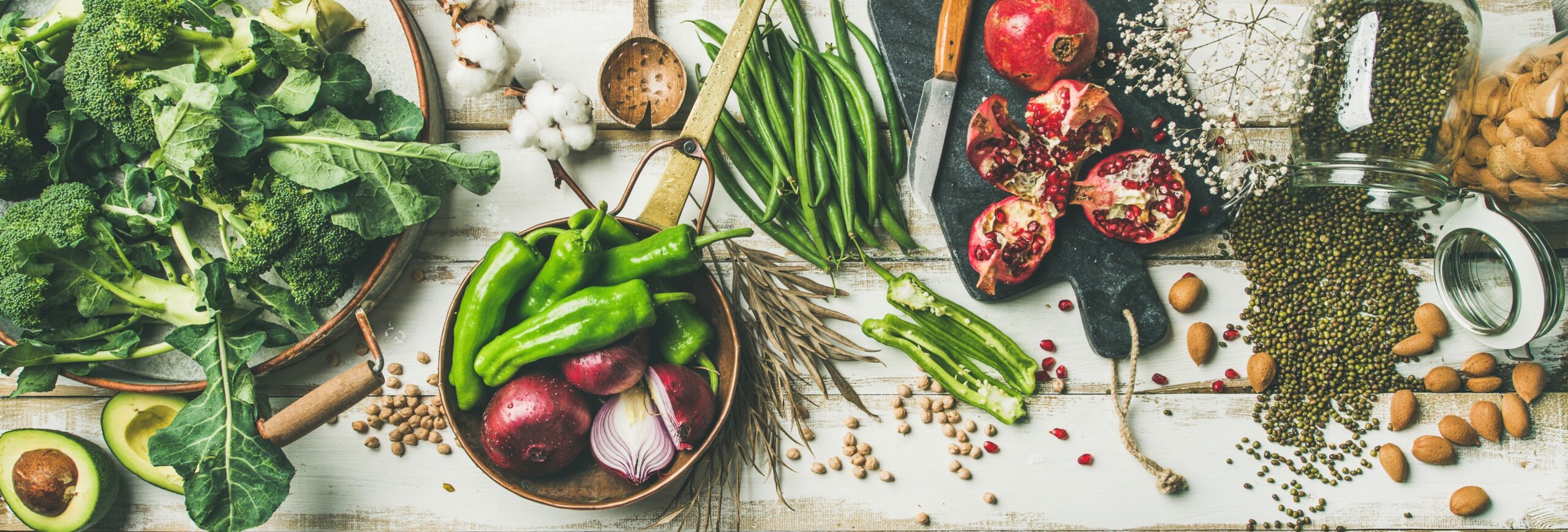 vegetarian, vegan food cooking ingredients. Flat-lay of vegetables, fruit, beans, cereals, kitchen utencil, dried flowers, olive oil over white wooden background.