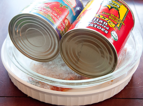 Two cans pressing salmon wrapped in plastic wrap.