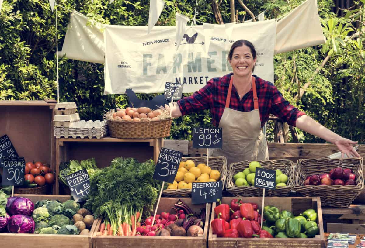 A woman farmer selling organic, seasonal produce at farmers market.